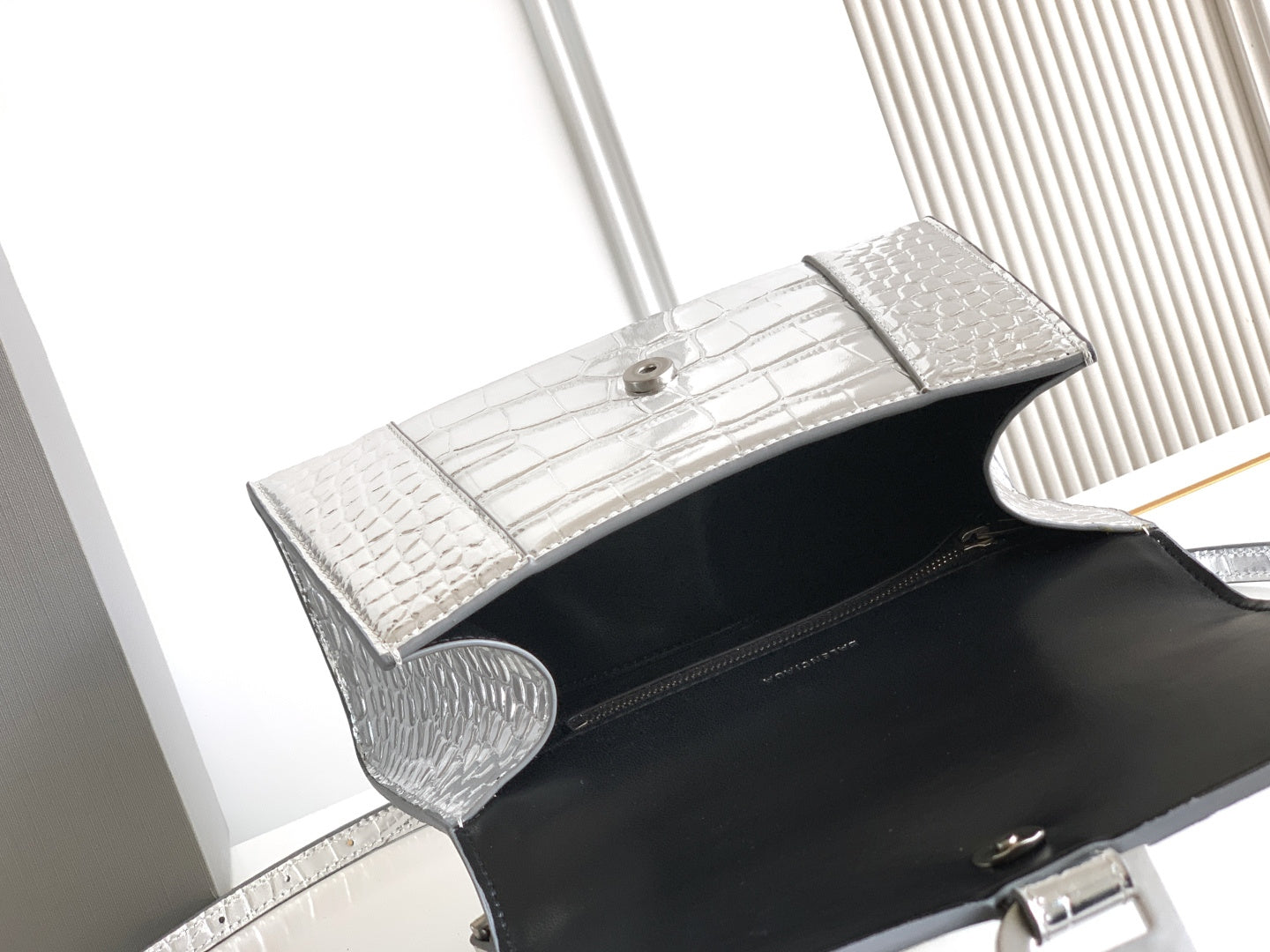 Silver croc-embossed flap bag with black interior and snap closure