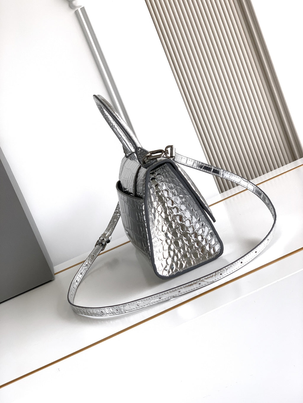 Silver croc-embossed mini bag with top handle, adjustable shoulder strap, and clasp