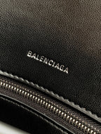 Black leather bag with Balenciaga lettering and visible zipper teeth