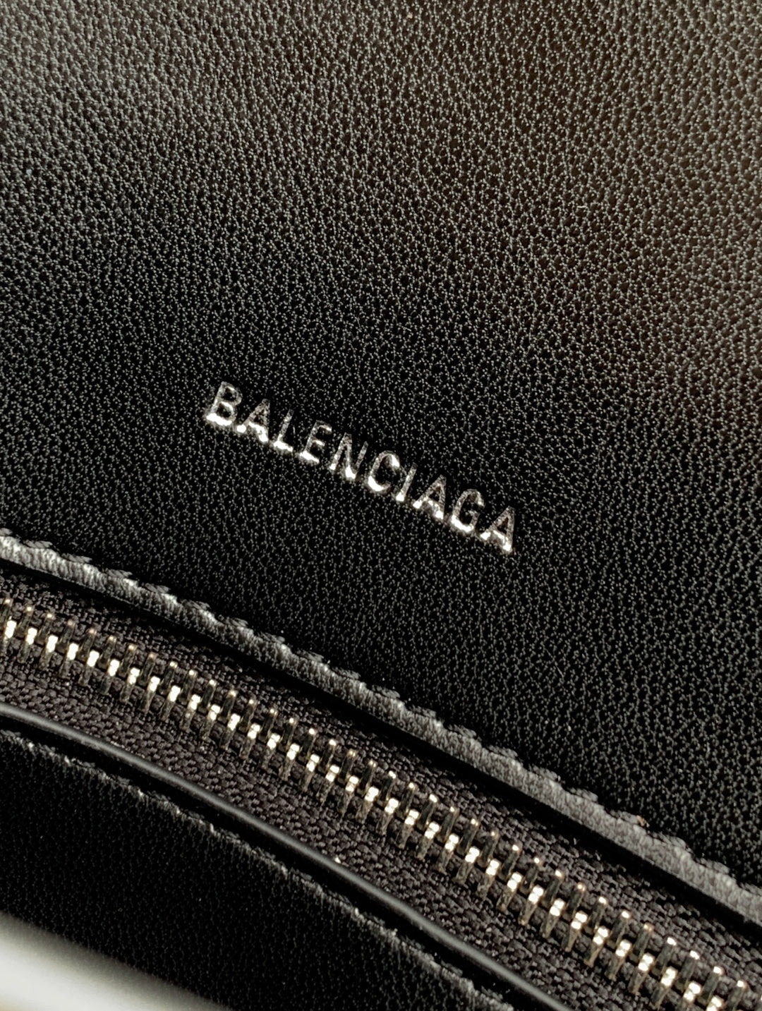 Black leather bag with Balenciaga lettering and visible zipper teeth