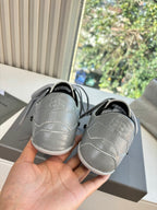 Light gray low-top sneakers, back view with black heel lining and rubber sole