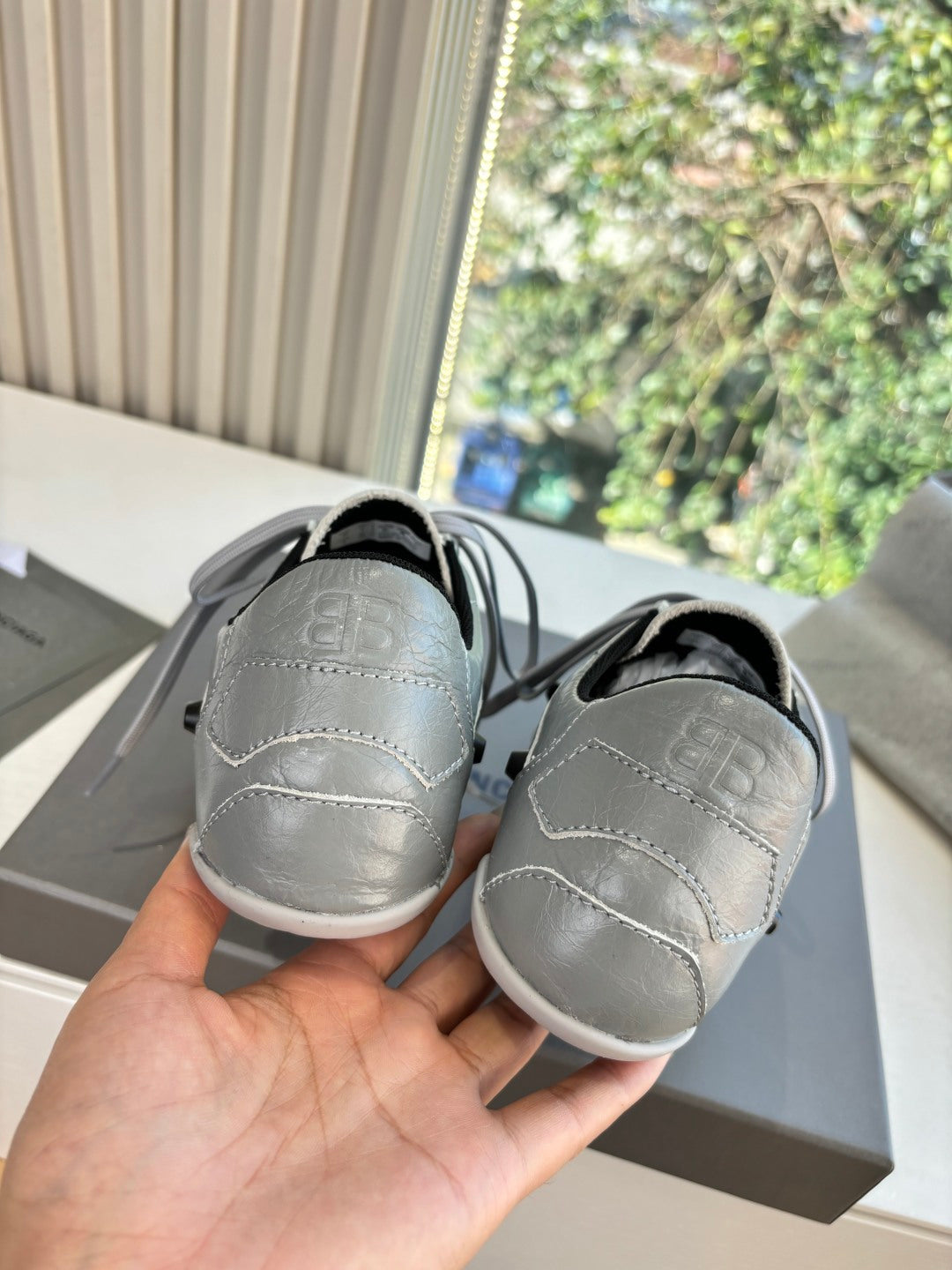 Light gray low-top sneakers, back view with black heel lining and rubber sole