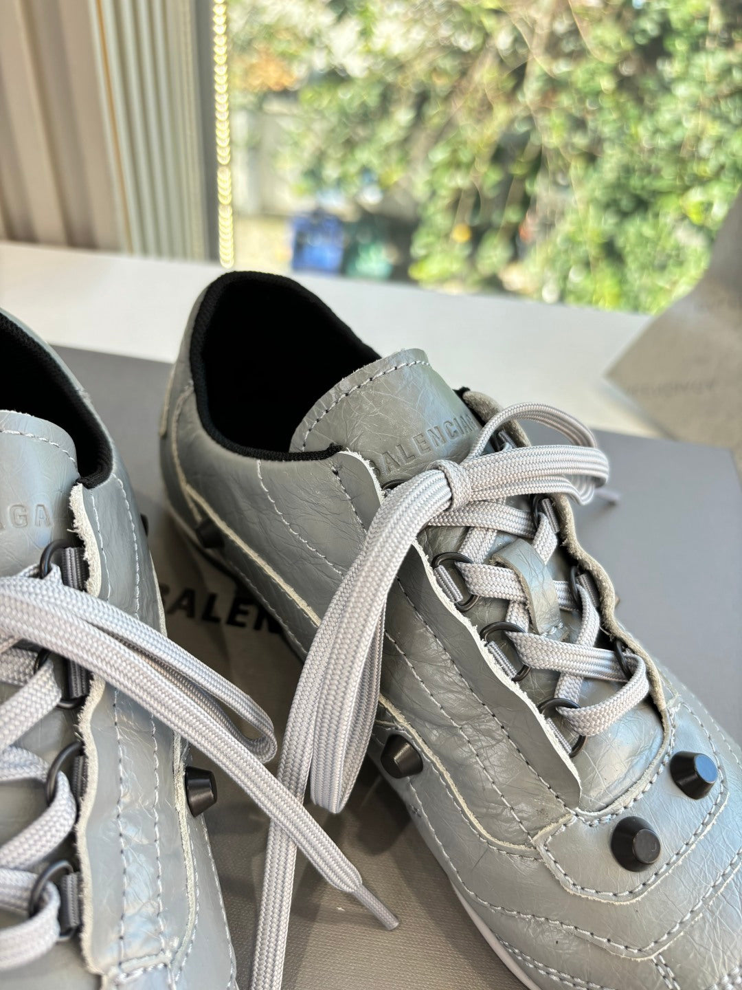 Close-up of light gray lace-up sneakers with laces, eyelets, and stitched overlays