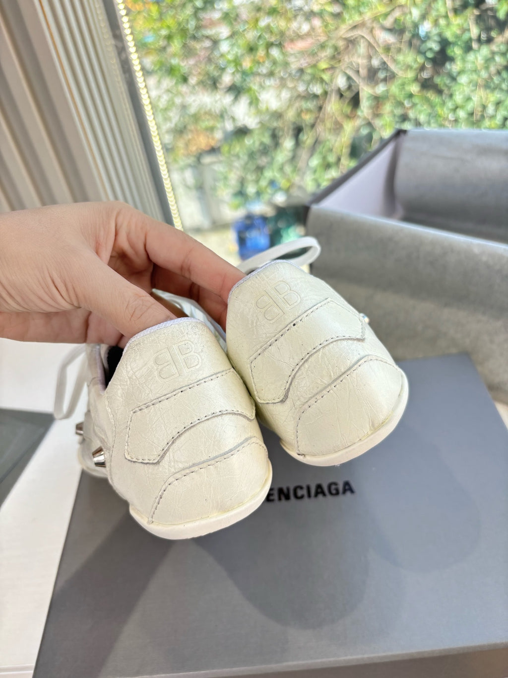 Cream low-top sneakers showing heel tab and back view with stamped logo