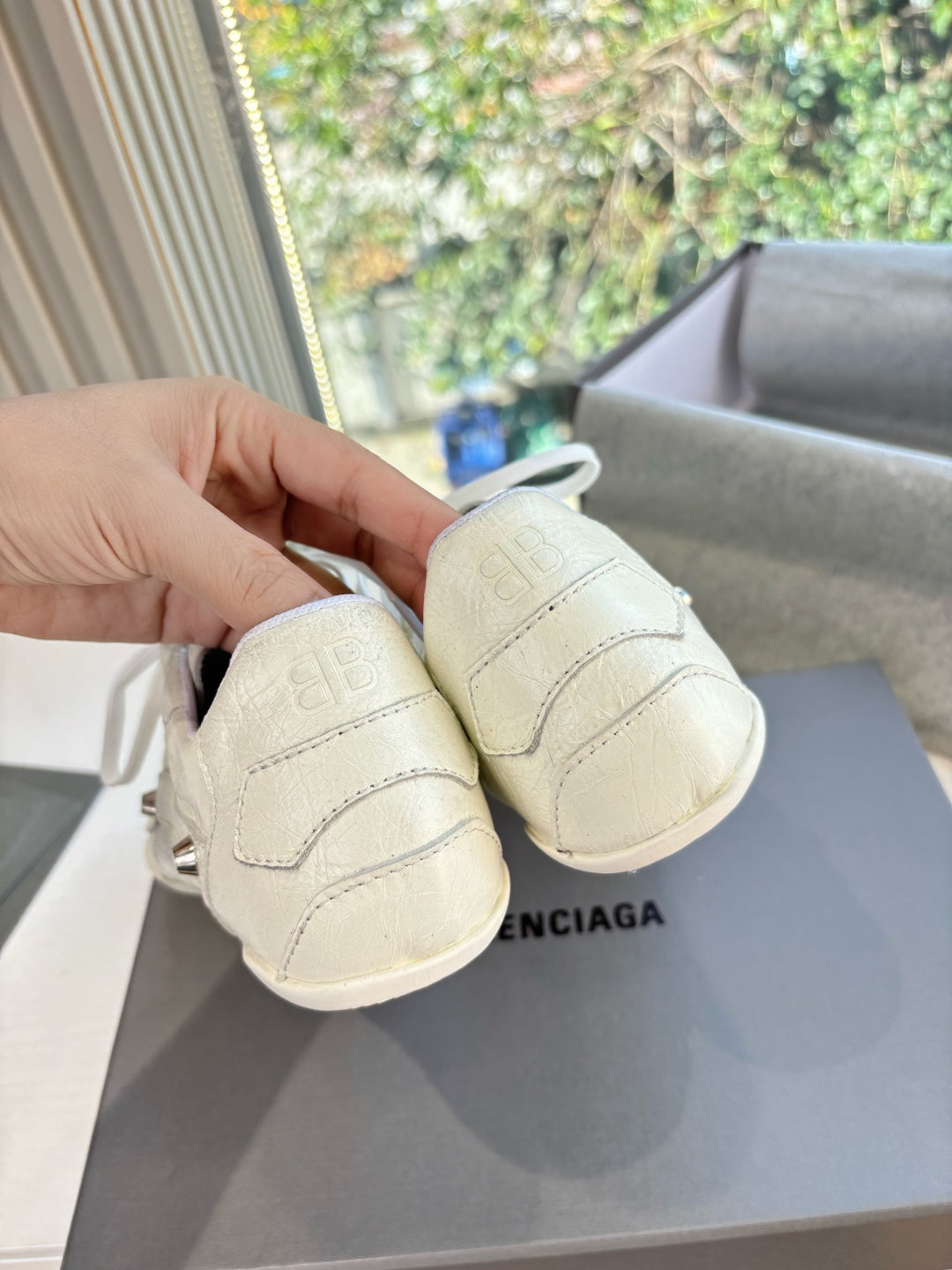 Cream low-top sneakers showing heel tab and back view with stamped logo