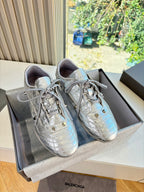 Silver metallic lace-up sneakers with textured upper and rounded toe.