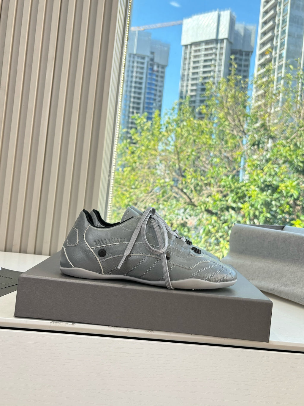 Light gray lace-up sneakers on a dark box, side angle view
