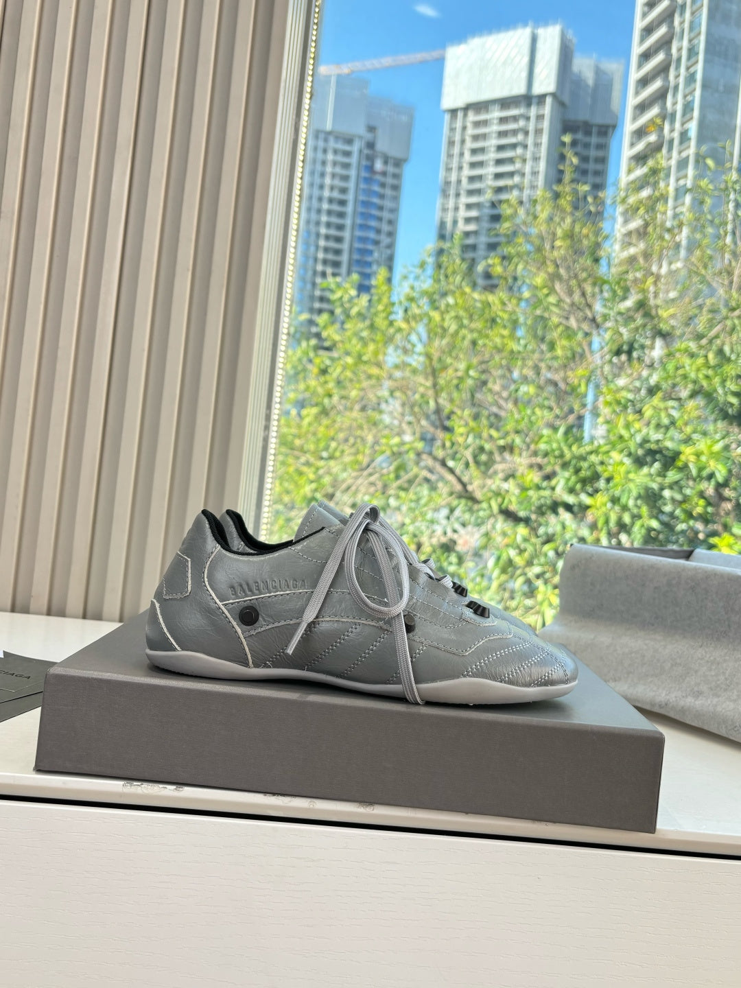 Light gray lace-up sneakers on a dark box, side angle view