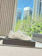 Cream lace-up sneakers posed on a box, with low profile and textured upper