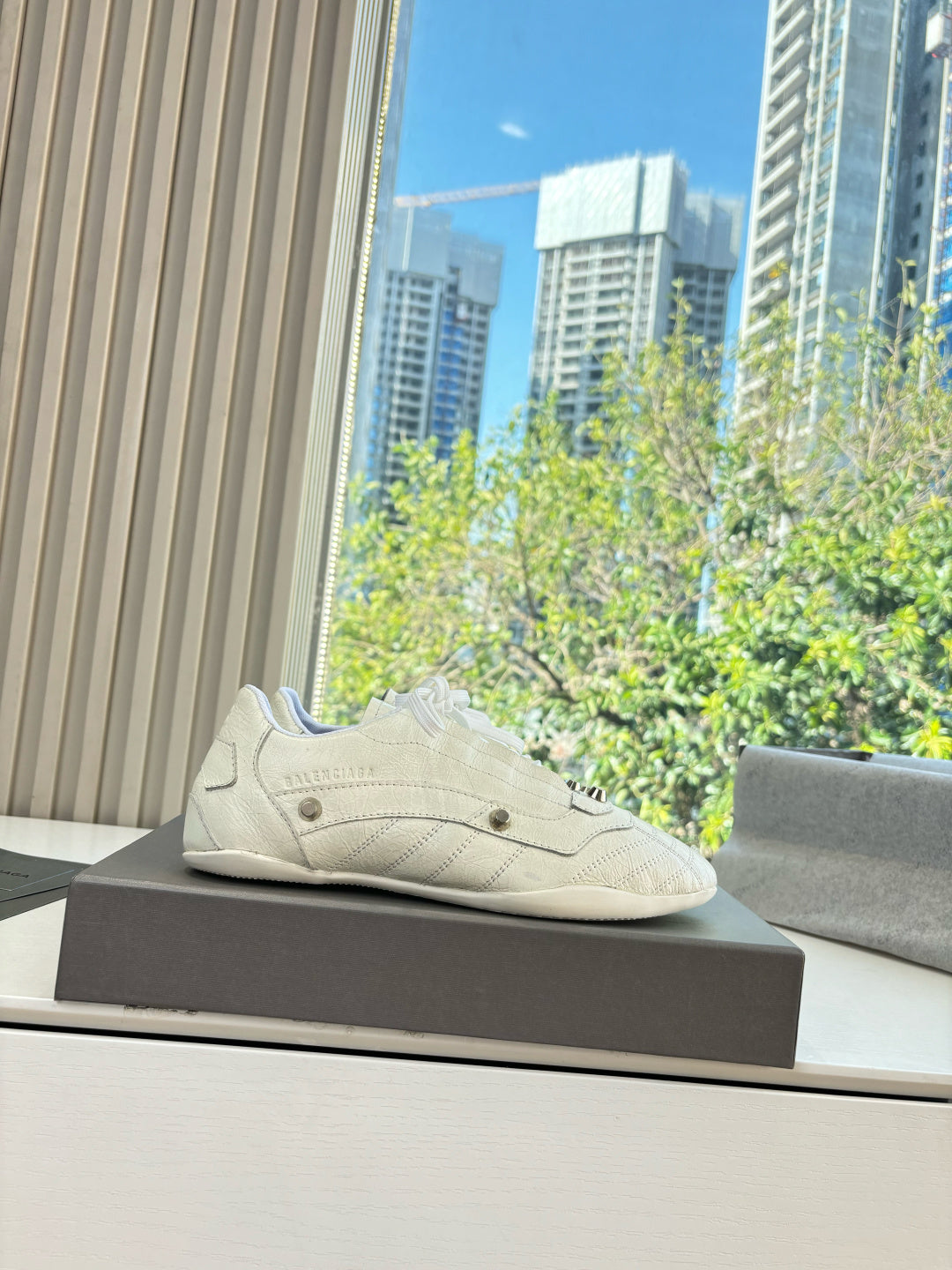 Cream lace-up sneakers posed on a box, with low profile and textured upper