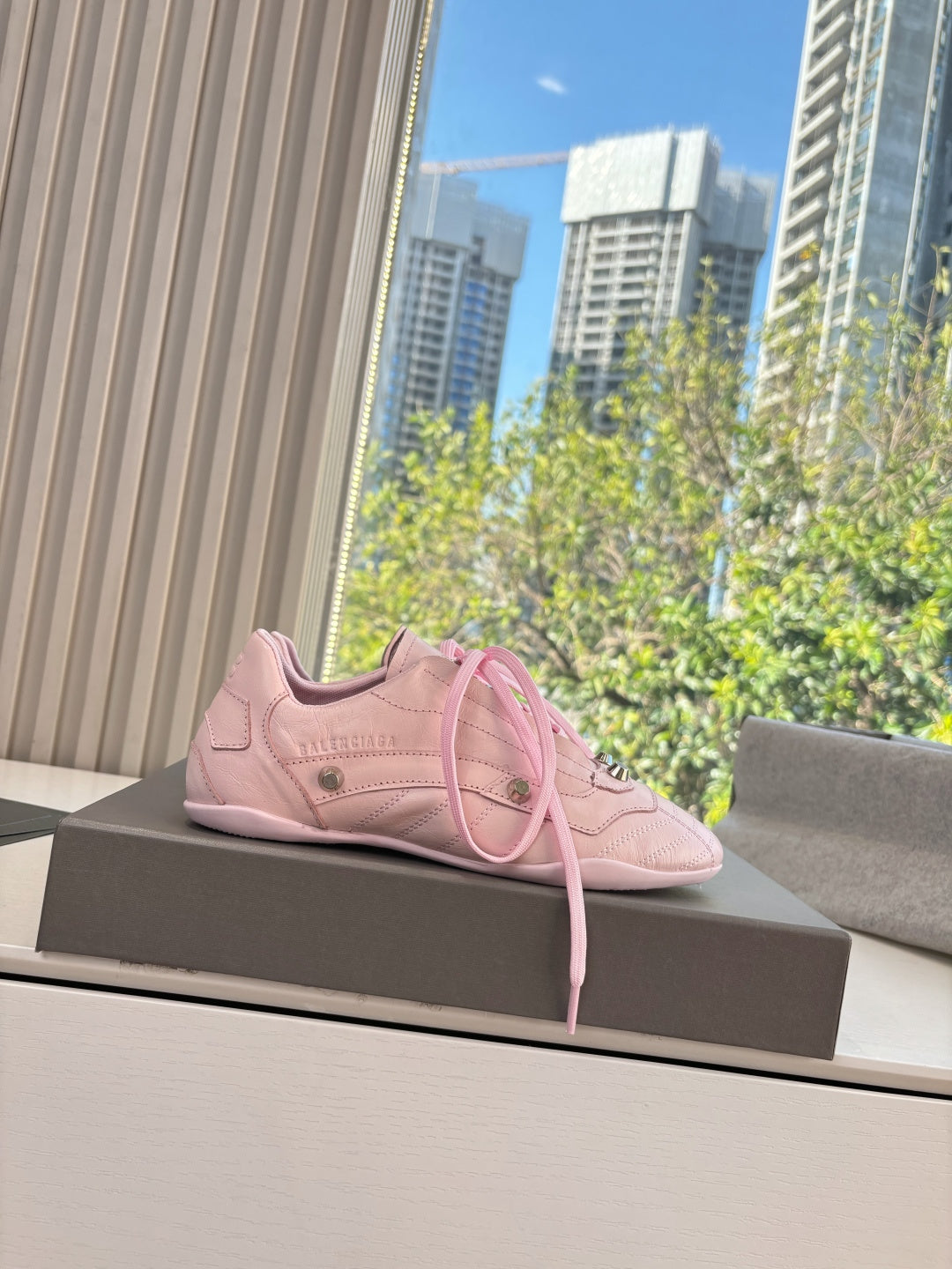 Women's pink lace-up sneakers on display pedestal with lace ties