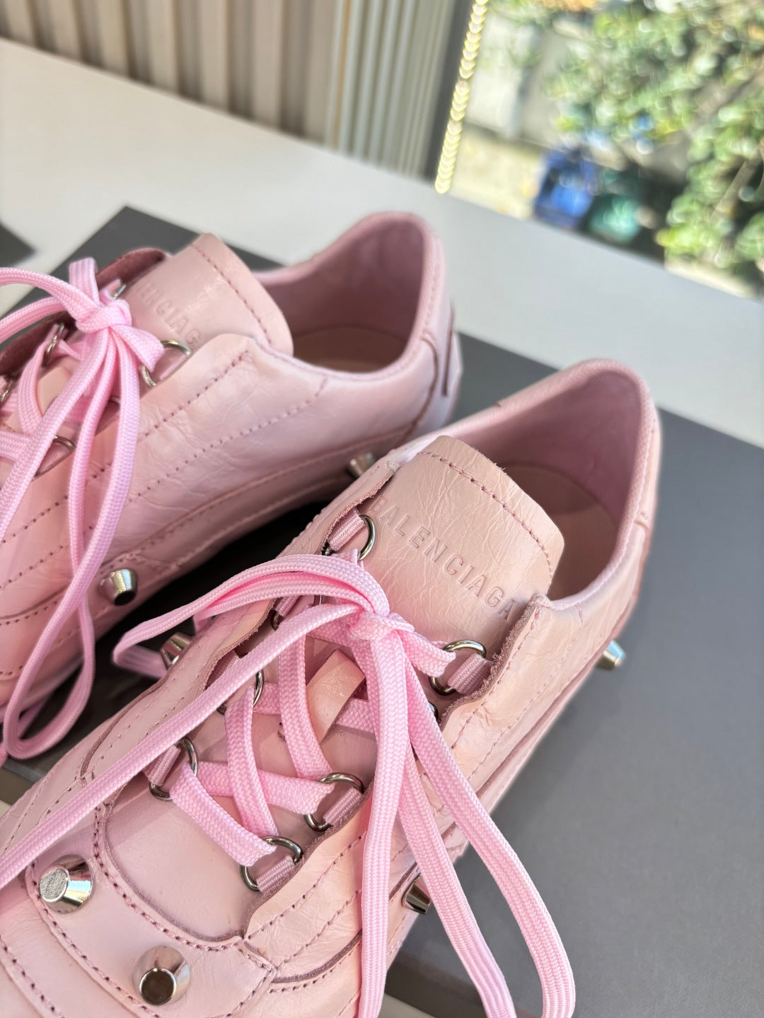 Women's pink lace-up sneakers close-up of eyelets, laces, and tongue logo