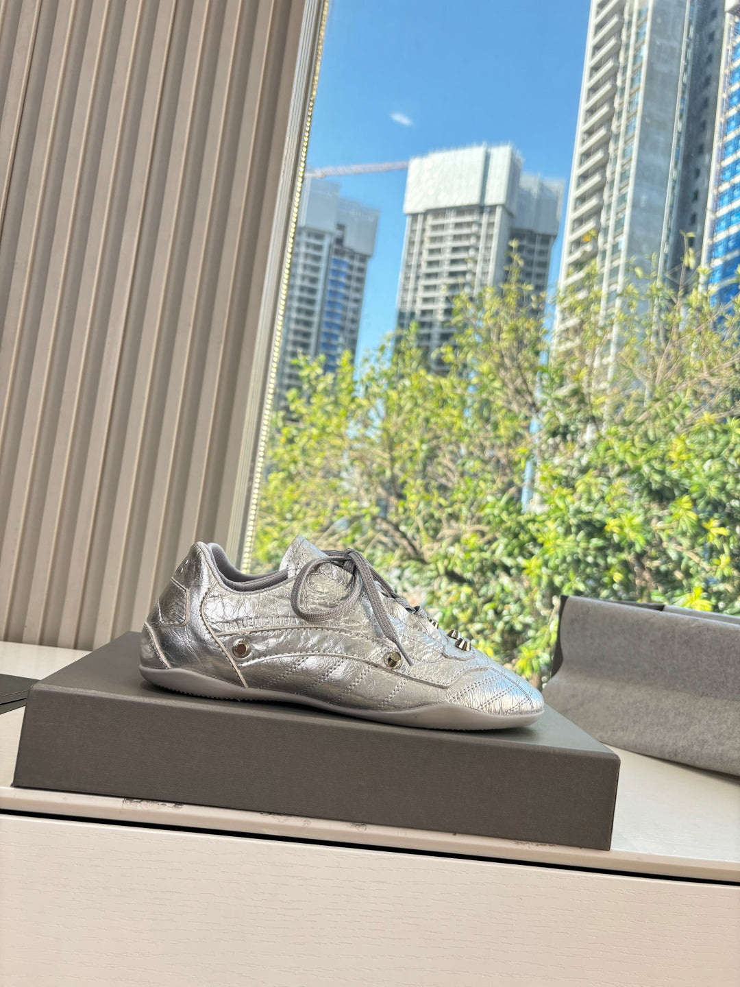 Silver metallic lace-up sneaker with textured finish and small logo patch.