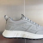 Dior unisex sneaker close-up in light gray mesh, lace-up tongue and side logo details