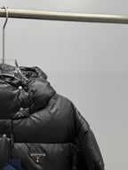 Prada black puffer jacket close-up of hood, buttons, and triangular logo patch