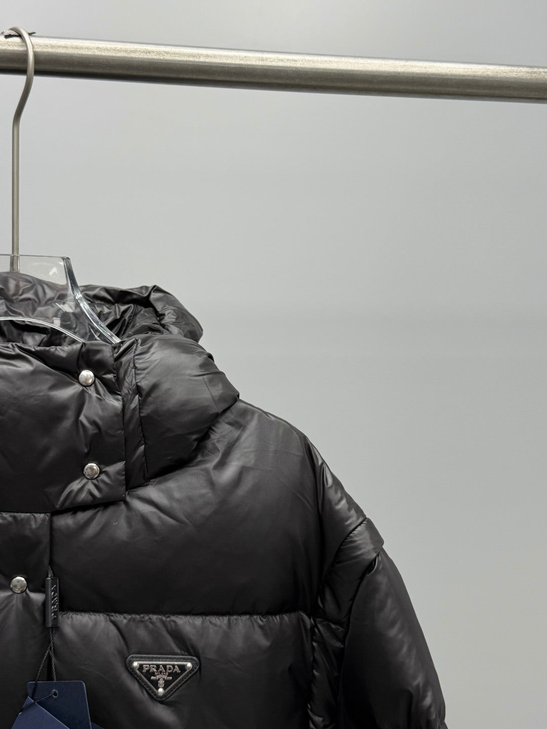 Prada black puffer jacket close-up of hood, buttons, and triangular logo patch