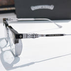 Close-up of black and silver eyeglass frame with patterned temple and clear lens.