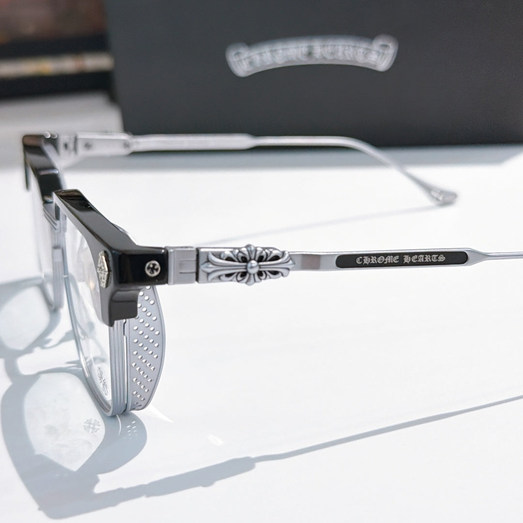 Close-up of black and silver eyeglass frame with patterned temple and clear lens.