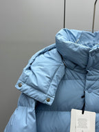 Light blue quilted puffer jacket with raised hood and snap buttons on shoulder