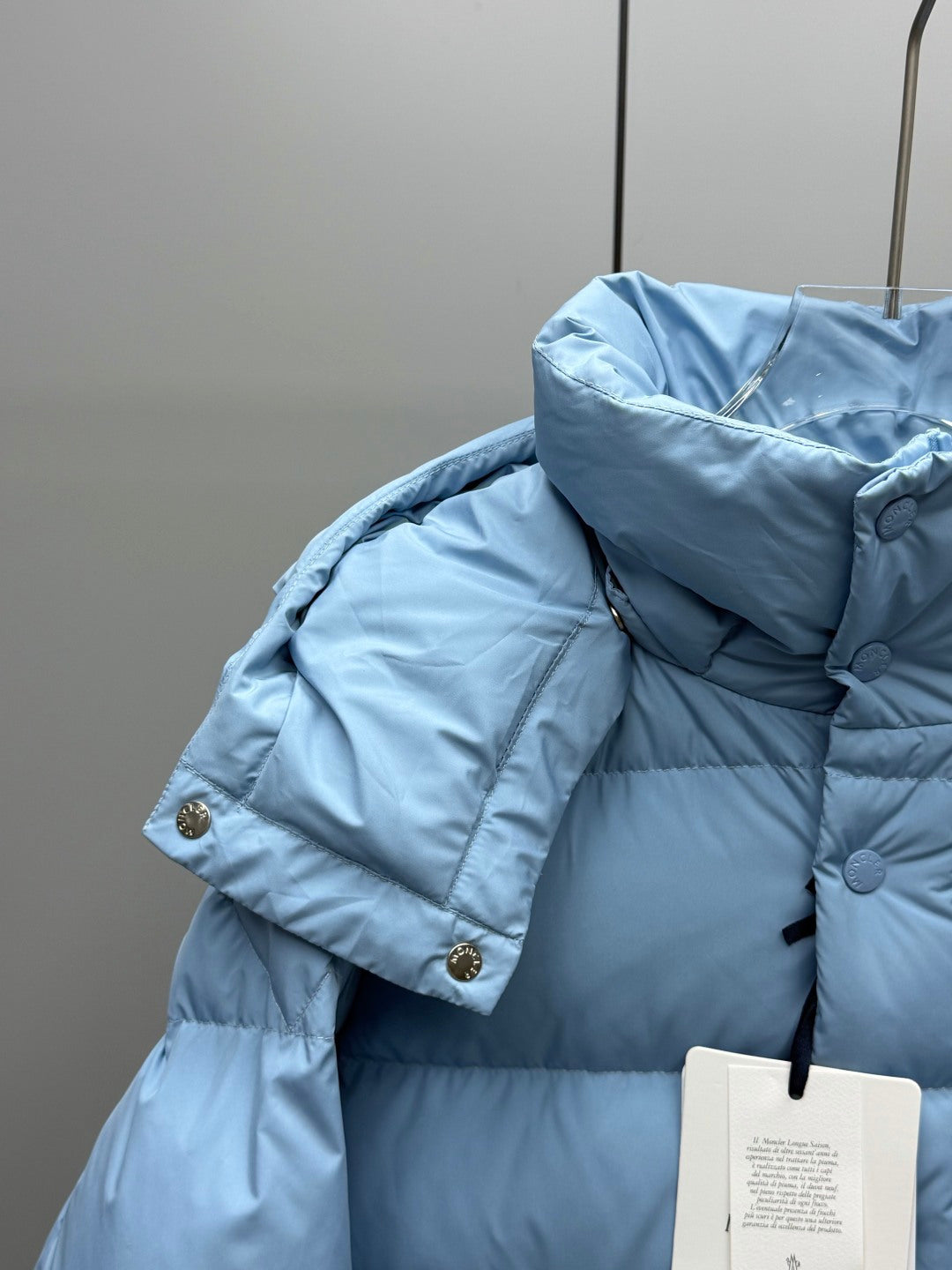 Light blue quilted puffer jacket with raised hood and snap buttons on shoulder
