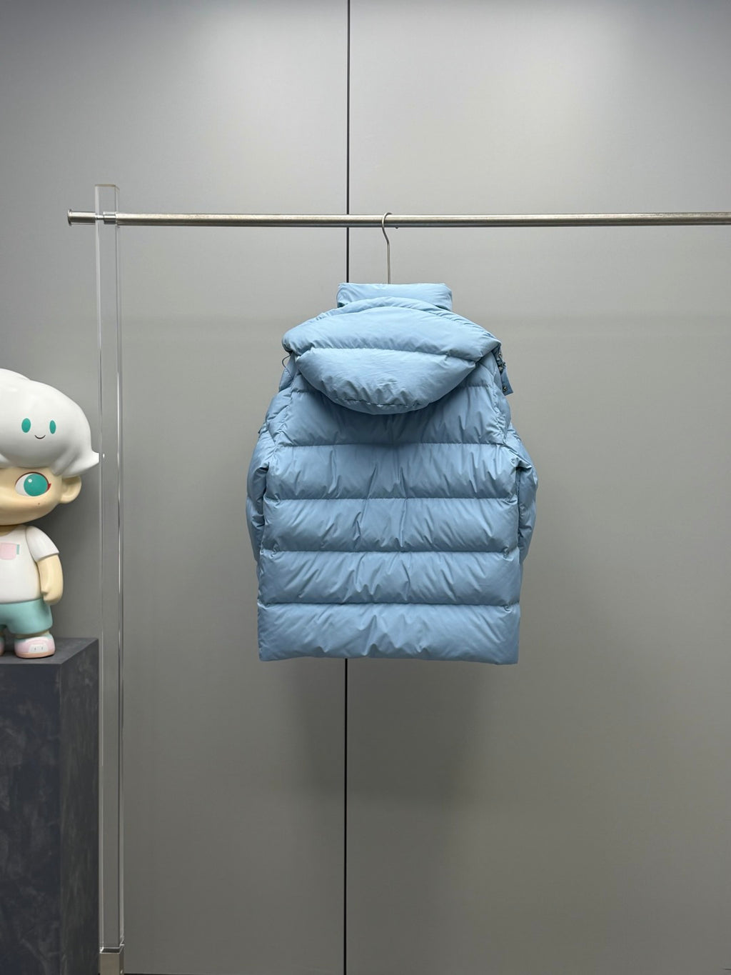 Light blue quilted puffer jacket with hood and front zipper, rear view