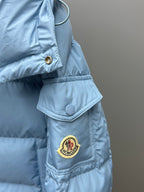 Light blue puffer jacket sleeve with circular snap and Moncler logo patch