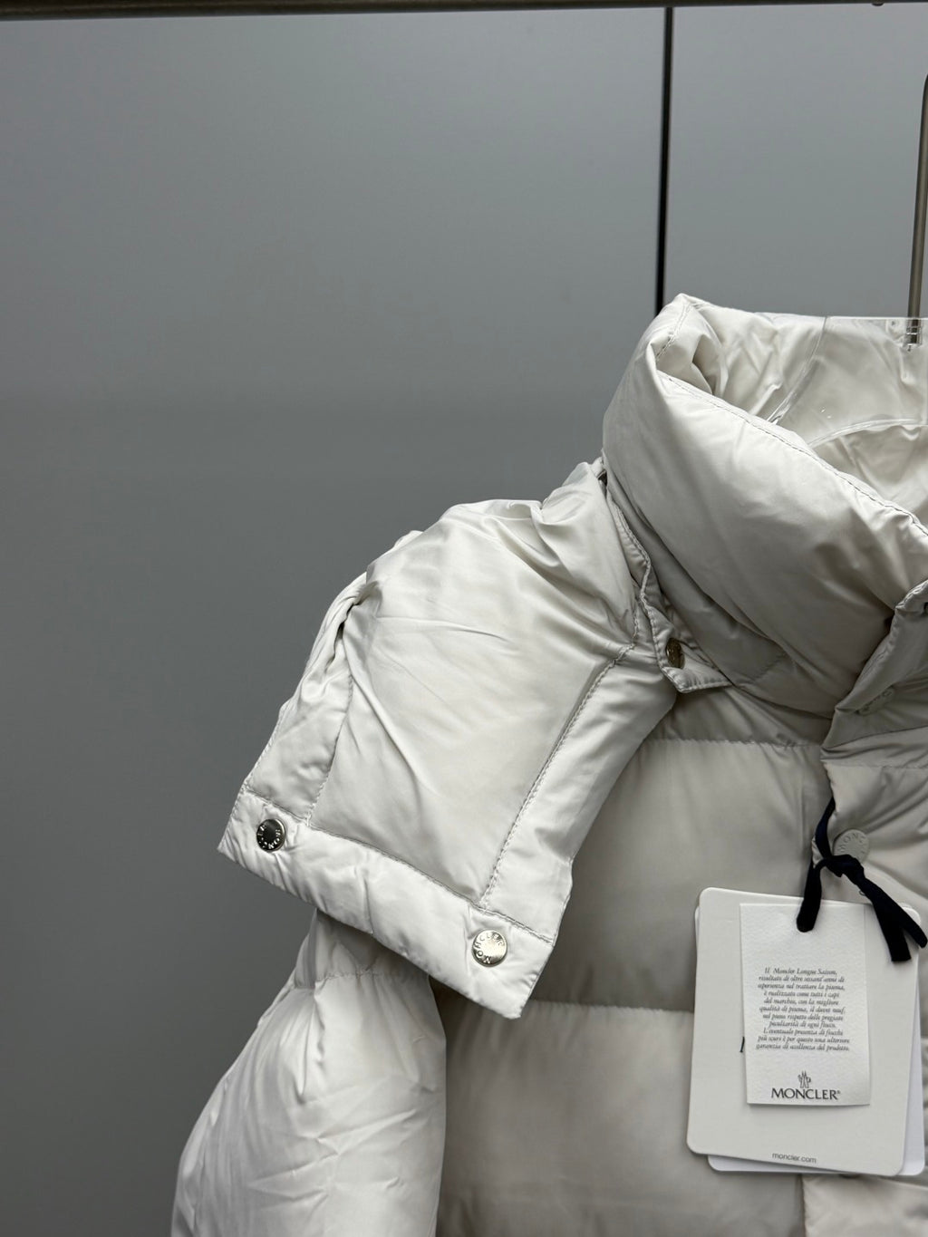 White puffer jacket shoulder and collar with button detail and attached tag