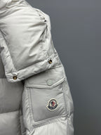 White quilted puffer jacket sleeve with embroidered emblem patch and gold buttons