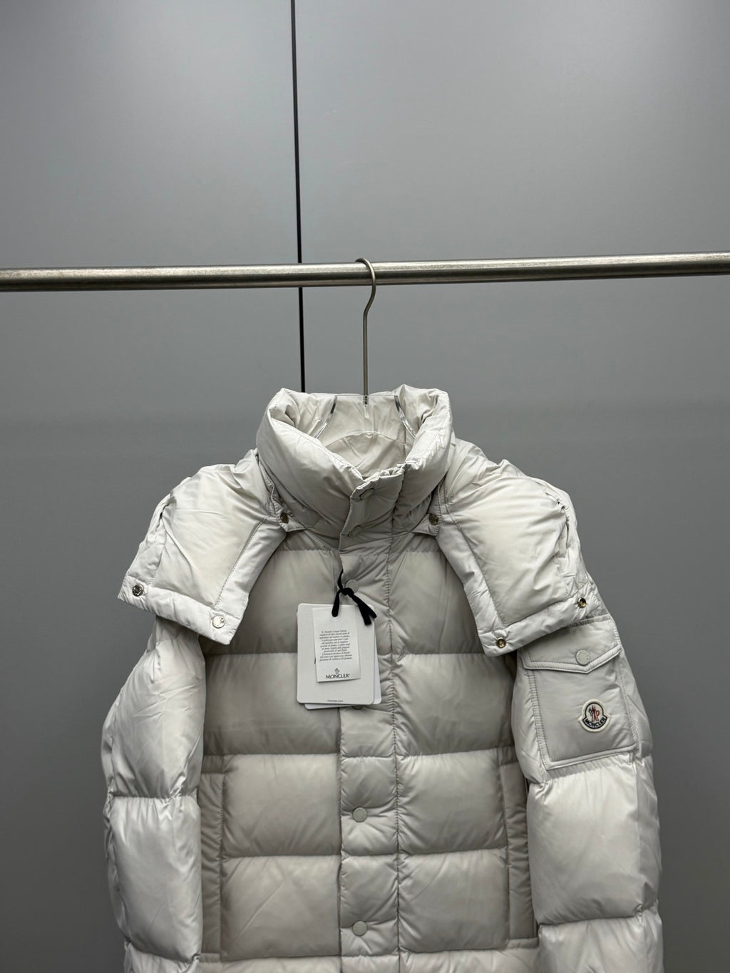 White long puffer jacket with hood, quilted front, and sleeve logo patch