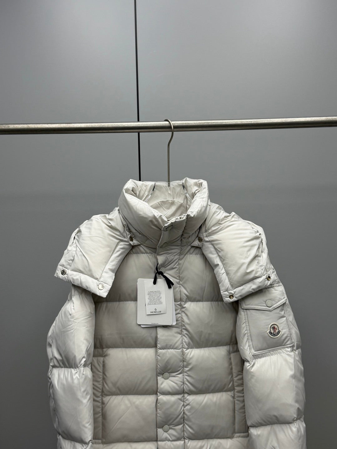 White long puffer jacket with hood, quilted front, and sleeve logo patch