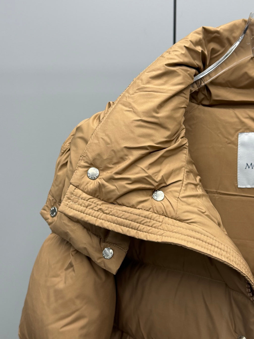 Moncler long puffer jacket in tan with hood, snap tabs, and metal buttons