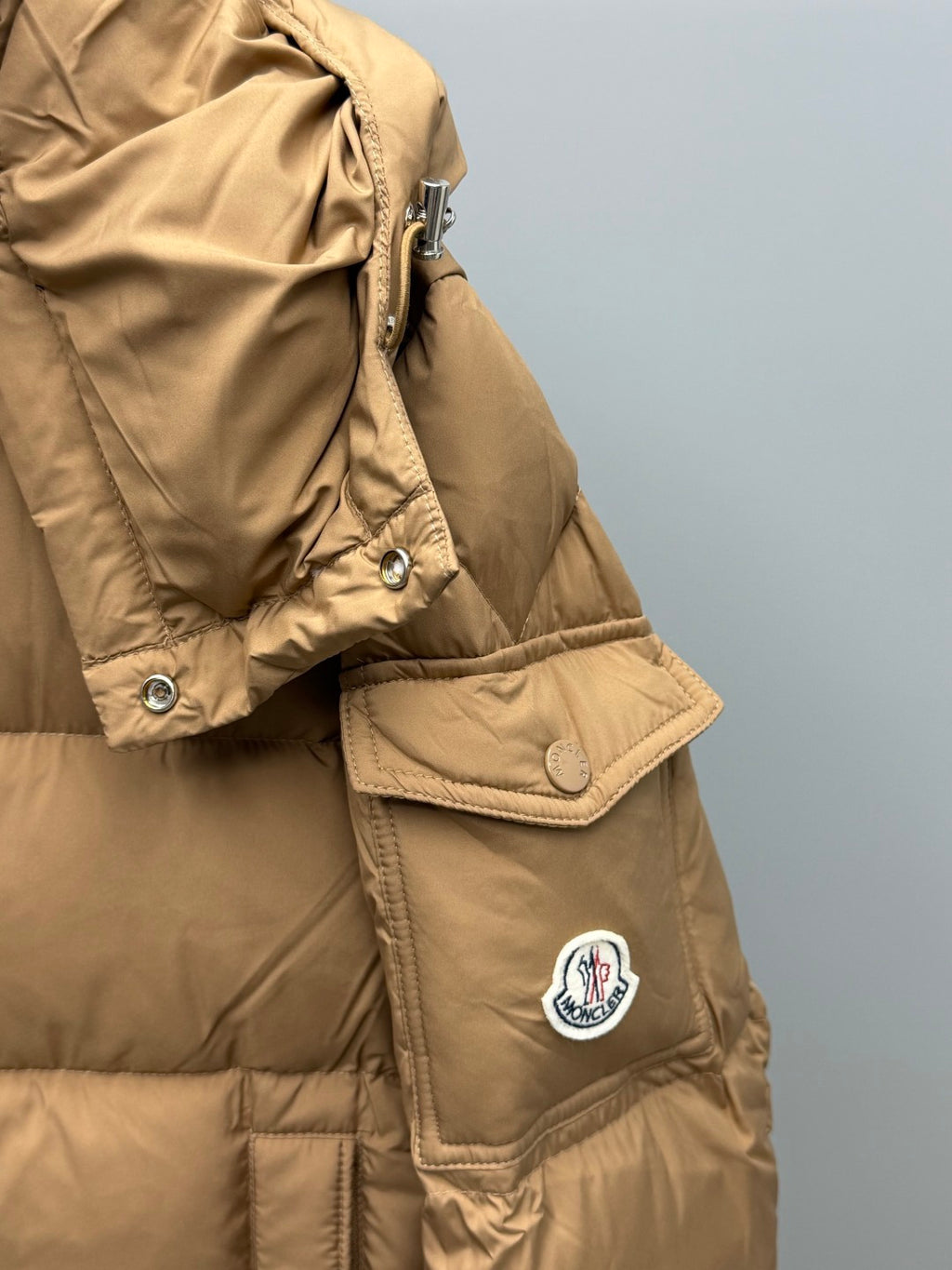 Moncler long puffer jacket in tan with patch logo, snap flap, and side pocket
