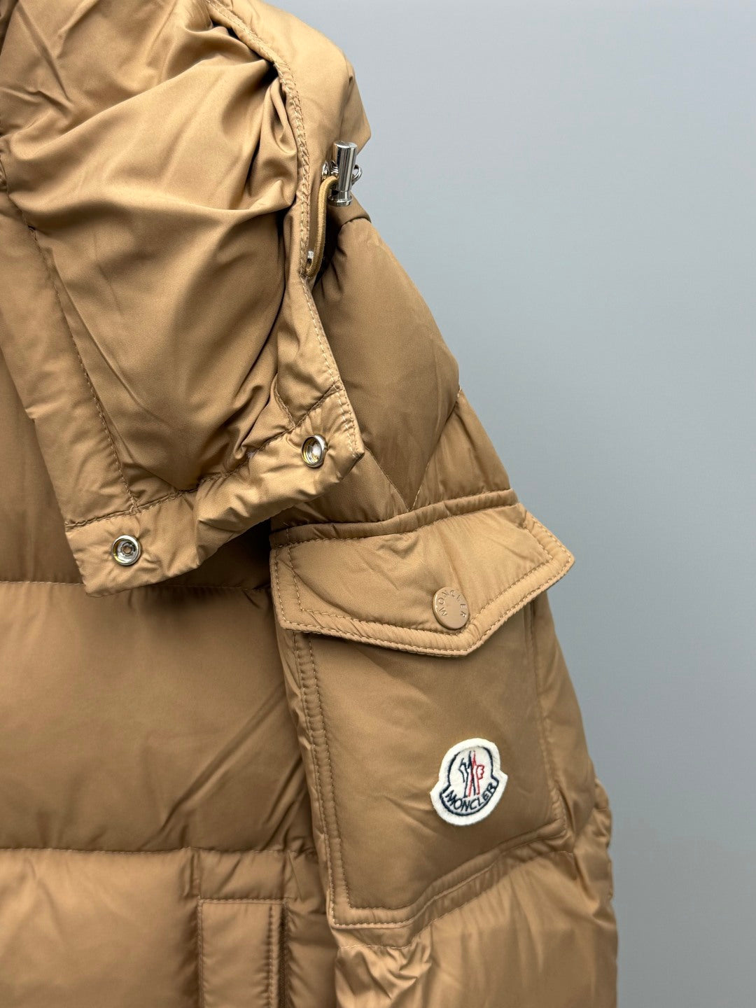 Moncler long puffer jacket in tan with patch logo, snap flap, and side pocket