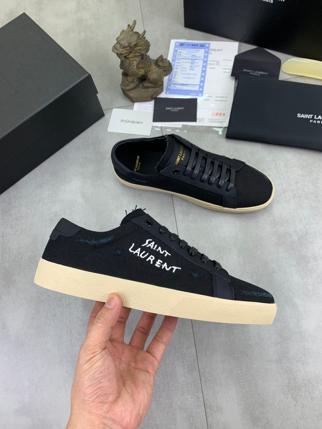 Navy SAINT LAURENT lace-up sneakers with beige sole held in hand