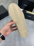 White sneaker outsole with beige herringbone tread and SAINT LAURENT mark.