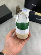 White sneaker heel with green leather panel and beige rubber sole.