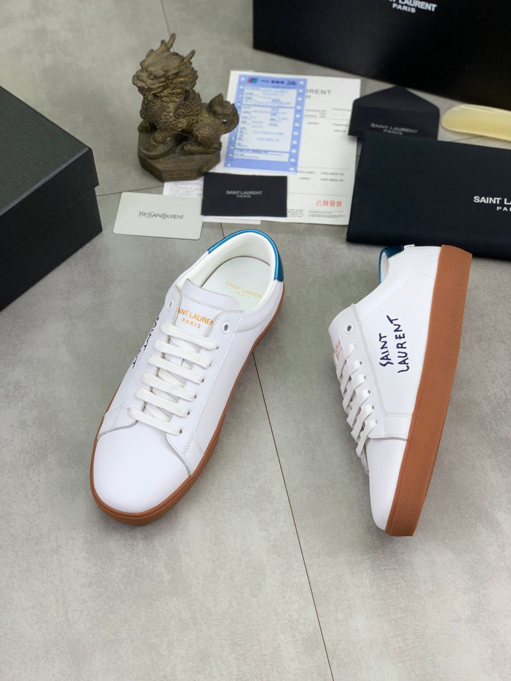 White leather sneakers with blue inner heel trim and brown gum soles