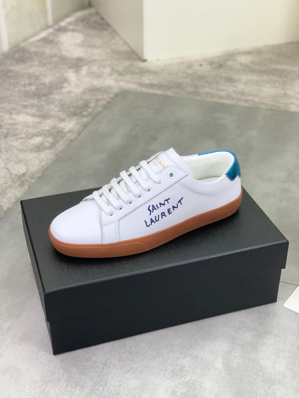 White leather low-top sneaker with blue collar and brown gum sole
