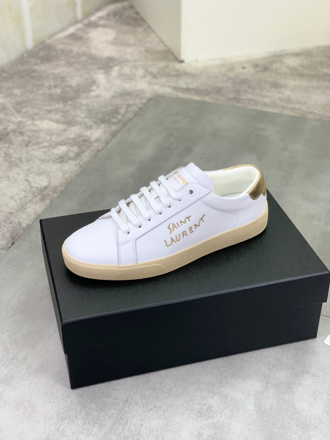 YSL unisex sneakers on a box, white lace-up design with tan gum sole and side logo.