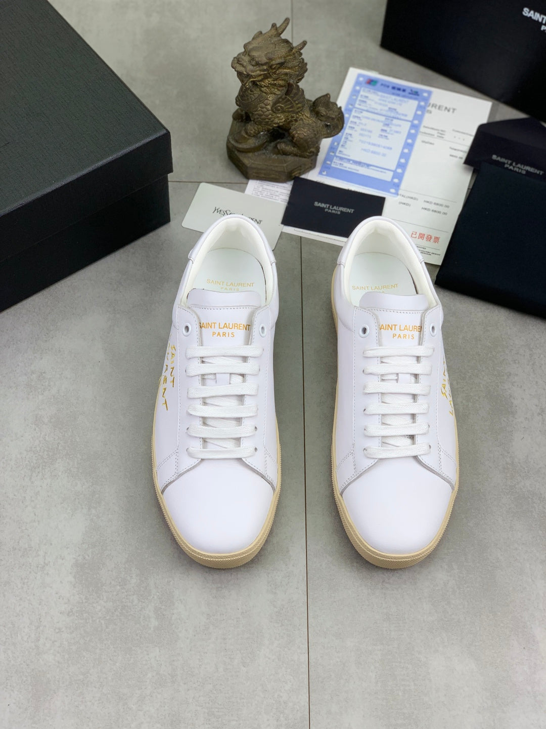 Pair of white lace-up low-top sneakers with beige soles and Saint Laurent branding