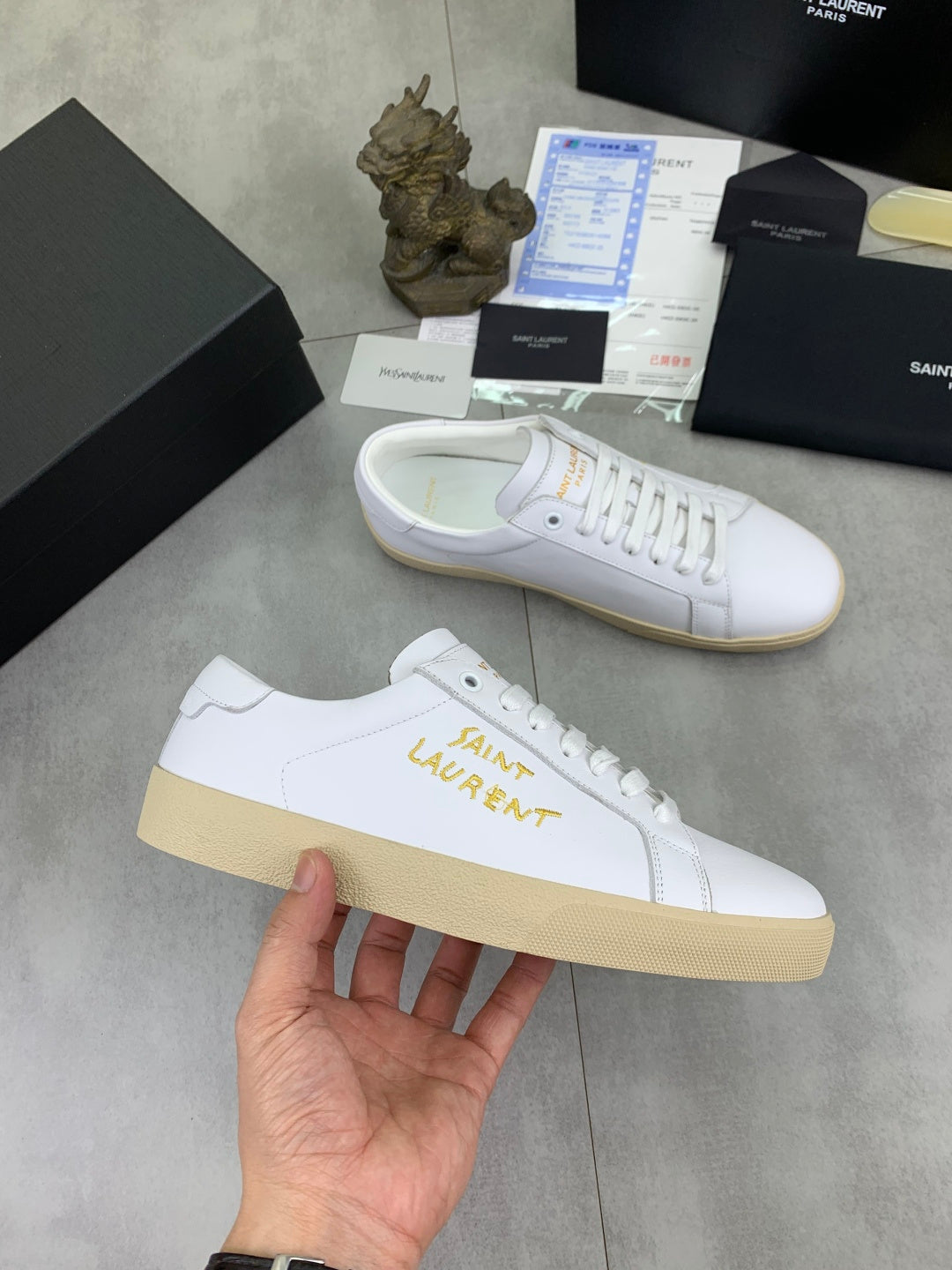 White lace-up sneaker with gold Saint Laurent logo on side and beige sole