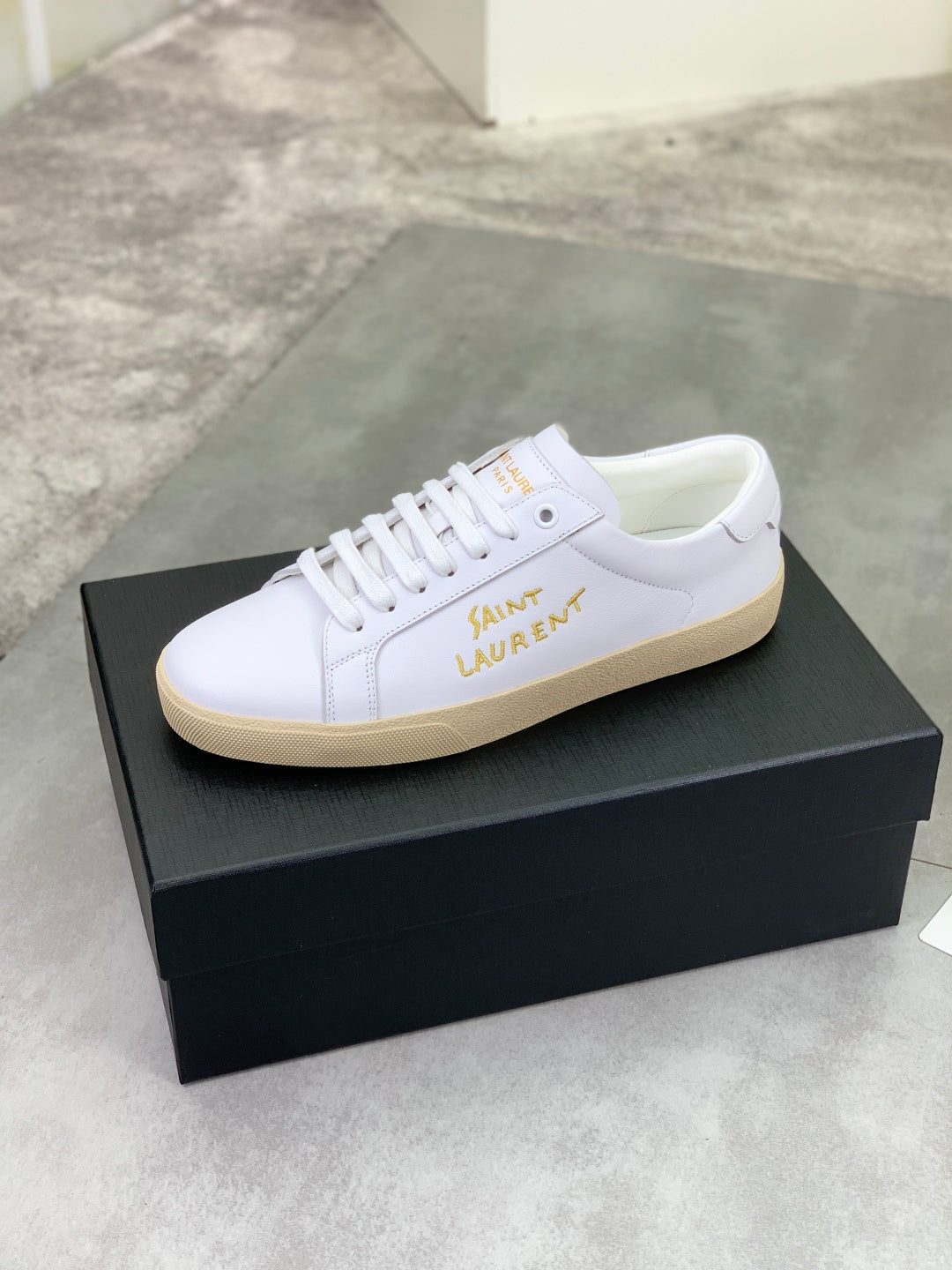 White leather low-top sneaker with lace-up closure and beige rubber sole