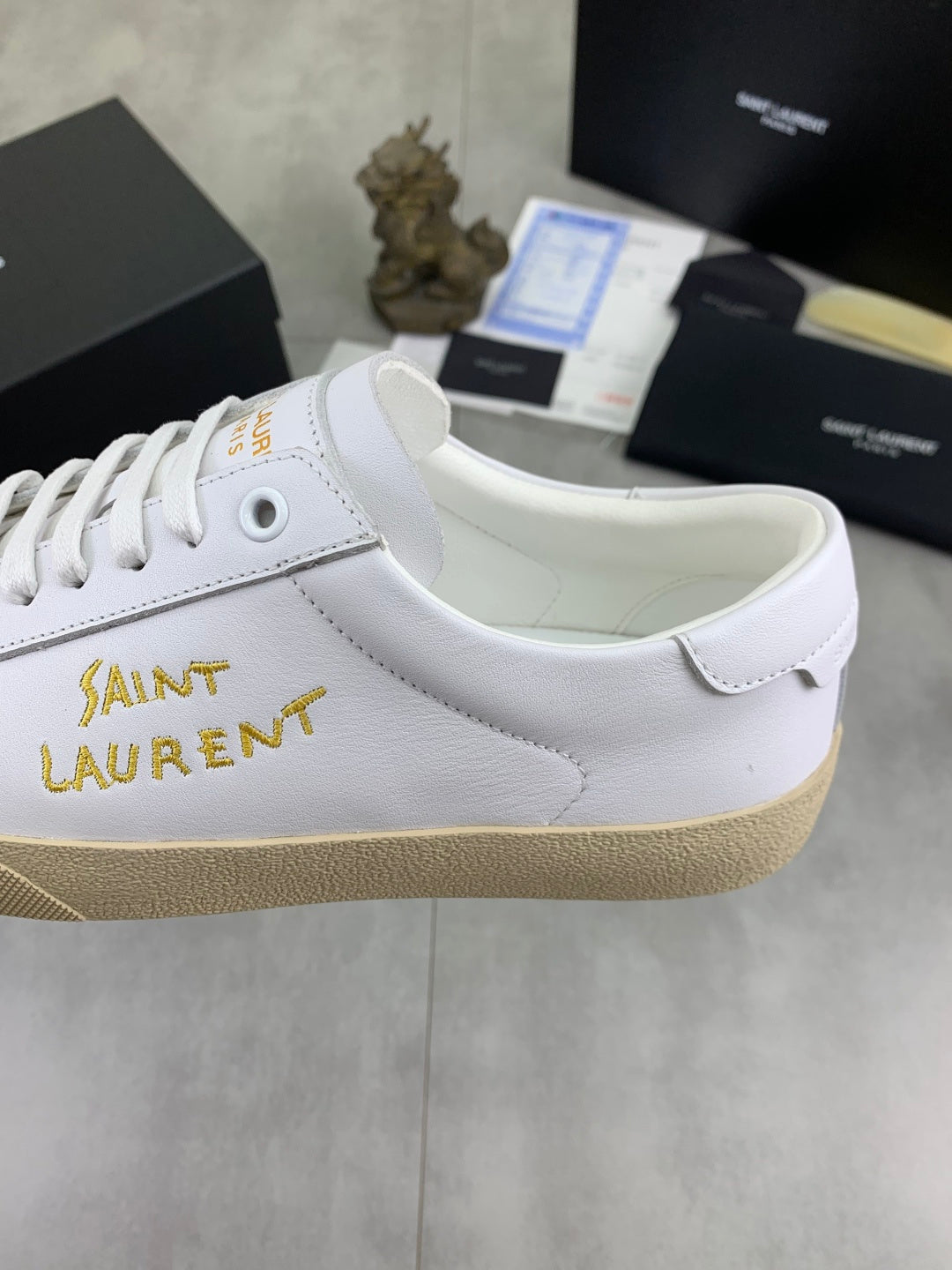 White sneaker side panel with gold Saint Laurent lettering and beige sole edge