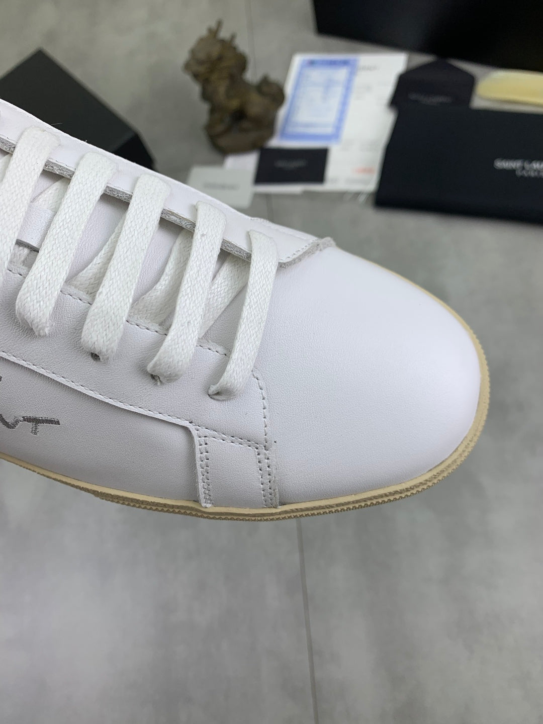 Luxury shoes toe view with white laces and white leather upper, beige edge sole.