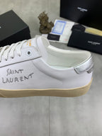 Luxury shoes with white leather upper, lace eyelets, and beige platform sole.