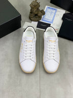 Pair of white low-top sneakers with gold side text and gum rubber soles
