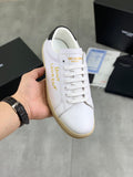 White low-top sneaker with gold text side, white laces, and gum rubber sole