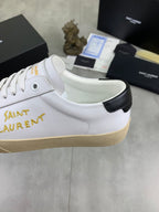 White low-top sneaker with gold Saint Laurent lettering and black heel collar