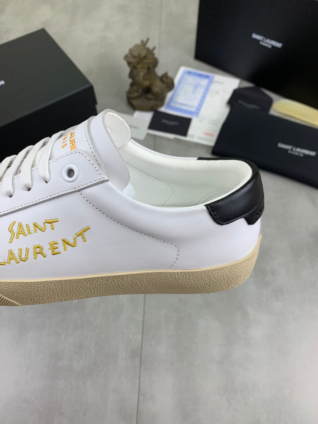 White low-top sneaker with gold Saint Laurent lettering and black heel collar