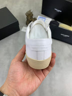 Back view of white YSL unisex sneakers in hand, leather heel and gum sole